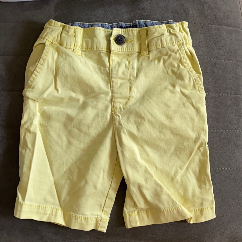 Yellow shorts with button closure.